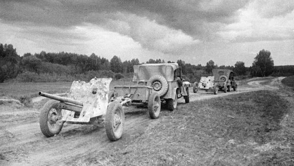 Машины ГАЗ-67 тянут по дороге артиллерийские орудия