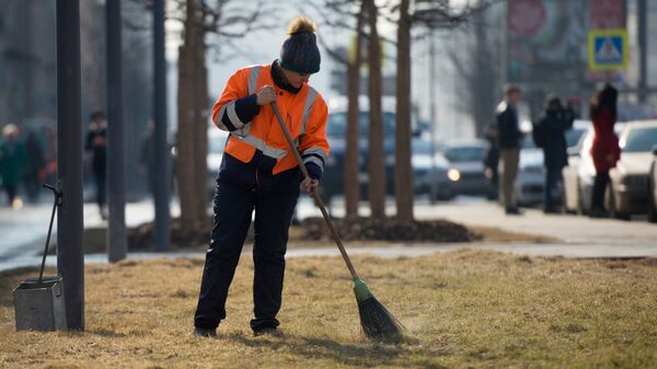 Работник коммунальных служб убирает улицу в Москве
