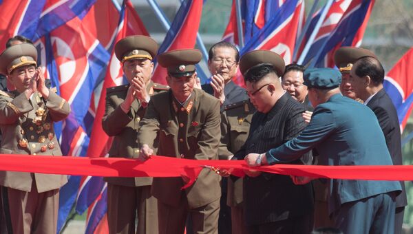 Глава КНДР Ким Чен Ын (первый справа) разрезает красную ленту во время торжественной церемонии открытия нового жилого комплекса на улице Рёмён в Пхеньяне
