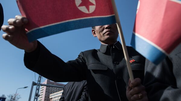 Жители города с флагами КНДР во время торжественной церемонии открытия нового жилого комплекса на улице Рёмён в Пхеньяне