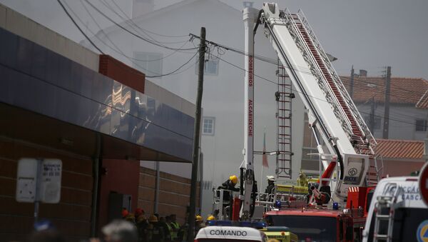 Пожарные на месте падения самолета на здание супермаркета недалеко от Лиссабона, Португалия. 17 апреля 2017
