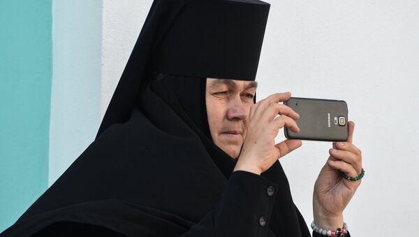 Монахиня фотографирует на мобильный телефон богослужение в Троице-Сергиевой лавре