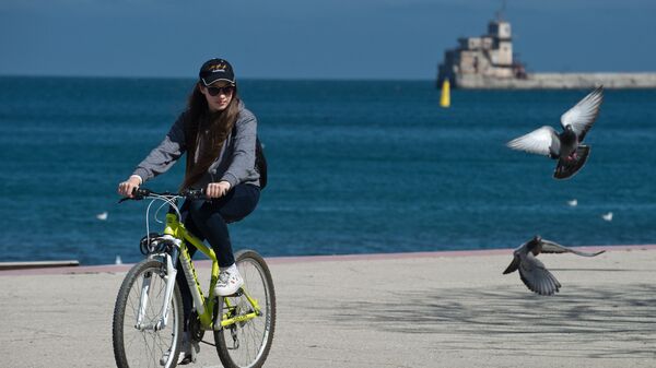 Девушка на велосипеде на набережной Феодосии