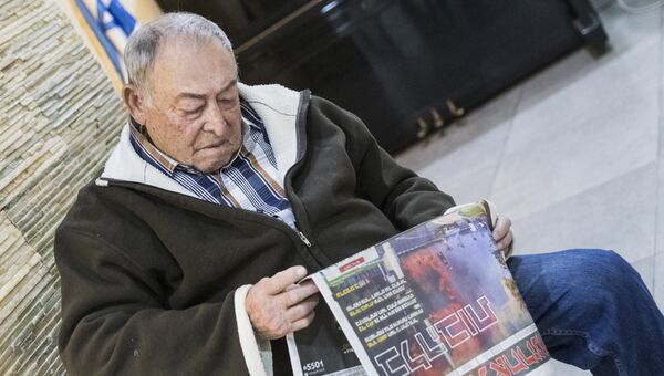 Мужчина читает газету в Хайфе, Израиль