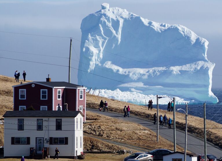 Жители Ферриленда рассматривают первый в этом сезоне айсберг, который дрейфует в месте под названием Аллея айсбергов, Канада