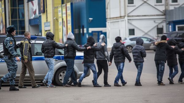 Сотрудник полиции ведет задержанных во время рейда на территории торгового-ярмарочного комплекса Москва в Люблино
