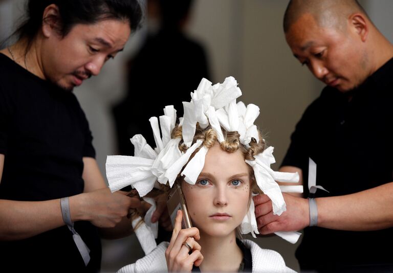 Стилисты делают прическу модели перед показом новой коллекции Christian Dior