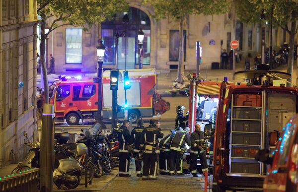 Сотрудники пожарной службы неподалеку от места перестрелки в Париже. Один полицейский погиб, еще один ранен при перестрелке в районе Елисейских полей в Париже