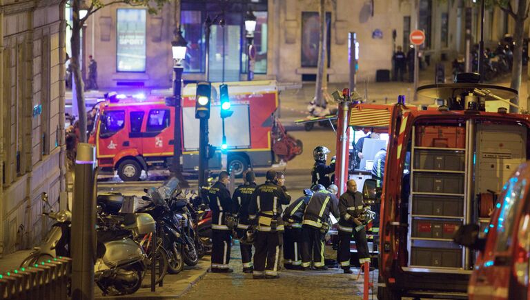 Сотрудники пожарной службы неподалеку от места перестрелки в Париже. Один полицейский погиб, еще один ранен при перестрелке в районе Елисейских полей в Париже