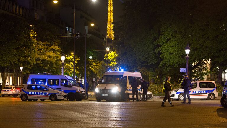 Сотрудники полиции стоят в оцеплении на месте перестрелки в Париже. Один полицейский погиб, еще один ранен при перестрелке в районе Елисейских полей в Париже