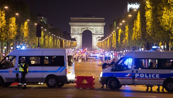 Сотрудники полиции стоят в оцеплении на месте перестрелки в Париже. Один полицейский погиб, еще один ранен при перестрелке в районе Елисейских полей в Париже