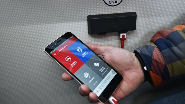 Пассажир заряжает телефон в салоне нового электробуса в Москве