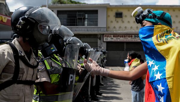 Сотрудники полиции и представители оппозиции во время первомайской демонстрации в Каракасе, Венесуэла