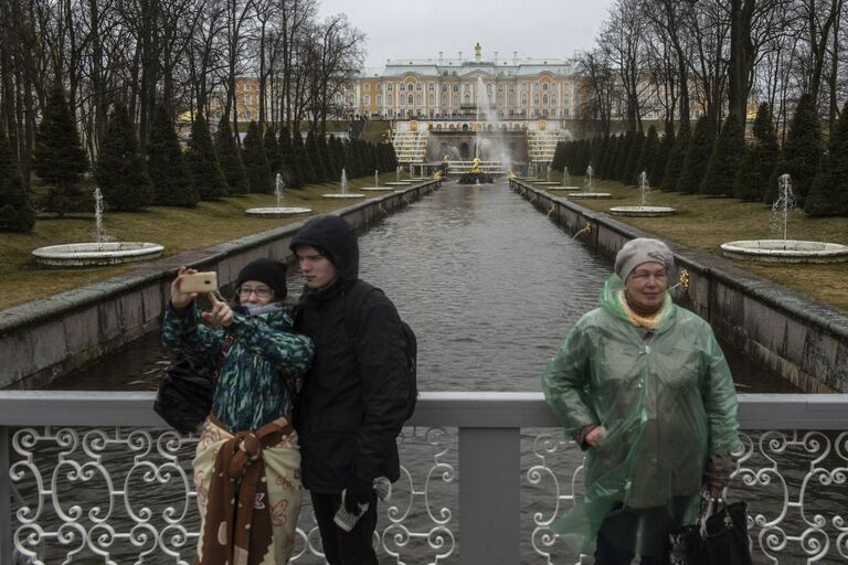 Горожане фотографируются на фоне фонтанов Большого каскада во время открытия нового летнего сезона в Государственном музее-заповеднике Петергоф