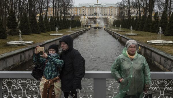 Горожане фотографируются на фоне фонтанов Большого каскада во время открытия нового летнего сезона в Государственном музее-заповеднике Петергоф