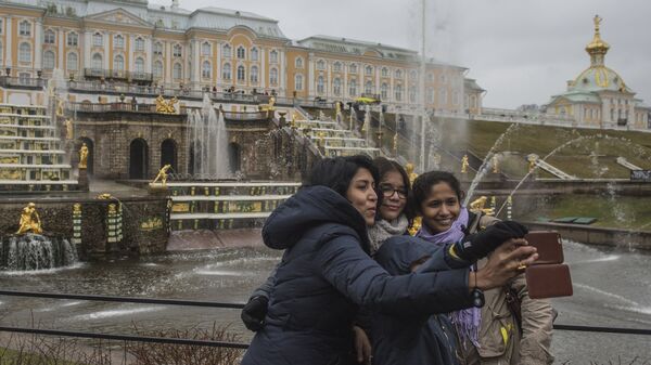 Туристы фотографируются на фоне фонтанов Большого каскада во время открытия нового летнего сезона в Государственном музее-заповеднике Петергоф