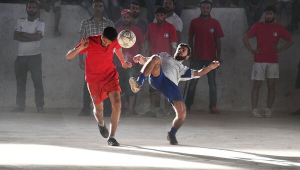Игроки во время футбольного матча между командами сотрудников общества Красного Креста и Красного Полумесяца и студентами в сирийском городе Дейр-эз-Зор
