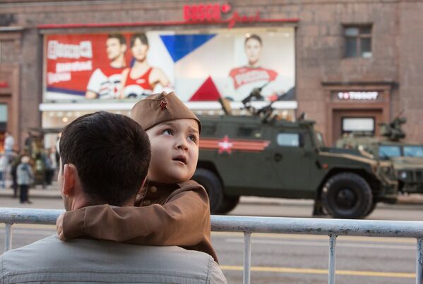 Мужчина с ребенком во время прохода военной техники по Тверской улице перед репетицией парада Победы на Красной площадии