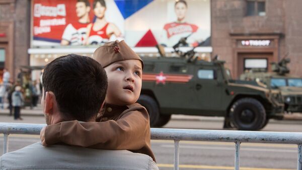 Мужчина с ребенком во время прохода военной техники по Тверской улице перед репетицией парада Победы на Красной площадии