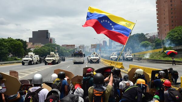 Представители оппозиции размахивают национальным флагом Венесуэлы в знак протеста против президента Николаса Мадуро в Каракасе. Архивное фото