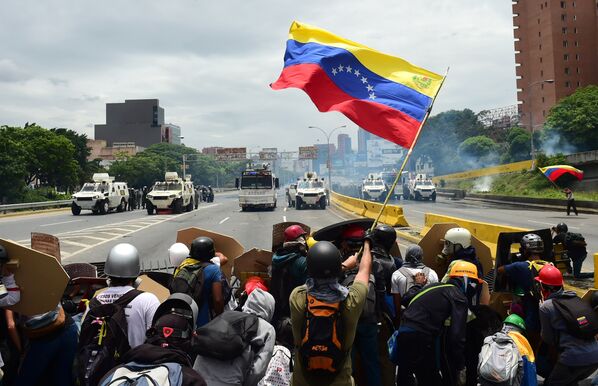 Представители оппозиции размахивают национальным флагом Венесуэлы в знак протеста против президента Николаса Мадуро в Каракасе. Венесуэла, 3 мая 2017