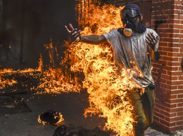 Демонстрант после взрыва бензобака полицейского мотоцикла во время столкновений в знак протеста против президента Венесуэлы Николаса Мадуро в Каракасе