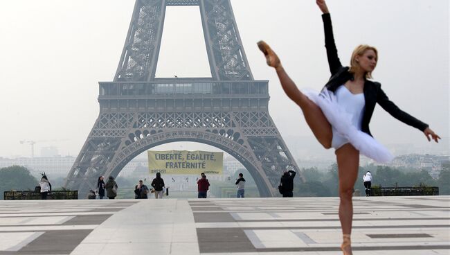 Балерина во время фотосессии на фоне Эйфелевой башни, на которой активисты Greenpeace устанавливают растяжку. 5 мая 2017
