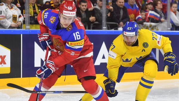 Игроки сборных России и Швеции Сергей Плотников и Виктор Хедман борются за шайбу.