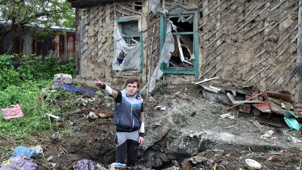 Подросток демонстрирует повреждения жилого дома, полученные в результате обстрела. Архивное фото