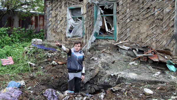 Подросток демонстрирует повреждения жилого дома, полученные в результате артиллерийского обстрела. Архивное фото