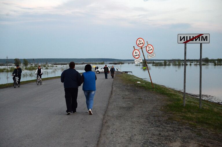 Местные жители на дороге в городе Ишим Тюменской области, подтопленной в результате сильного поднятия воды в реках Ишим и Карасуль