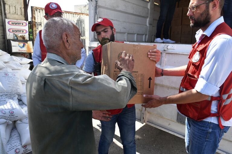Представители Сирийского арабского красного полумесяца раздают гуманитарную помощь жителям квартала Кабун в пригороде Дамаска