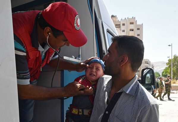 Представители Сирийского арабского красного полумесяца оказывают медицинскую помощь жителям квартала Кабун в пригороде Дамаска