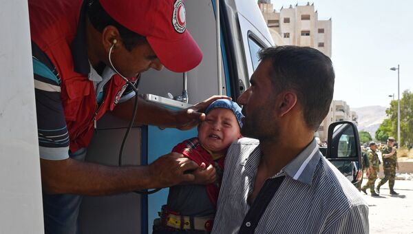 Представители Сирийского арабского красного полумесяца оказывают медицинскую помощь жителям квартала Кабун в пригороде Дамаска