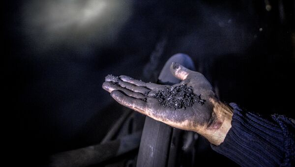 Шахтер показывает уголь на шахте Глубокая в Шахтерске