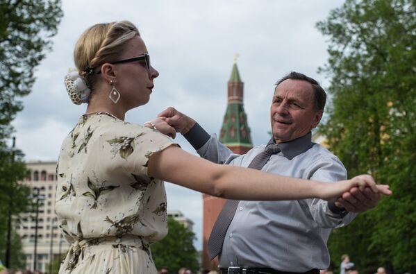 Мужчина и женщина танцуют во время открытия концертной программы Военные оркестры в парках