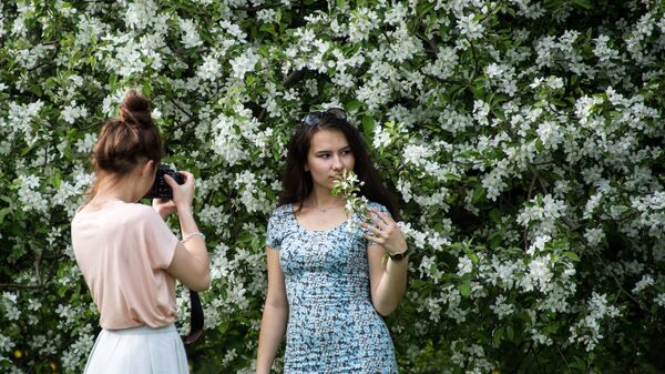 Девушки фотографируются в яблоневом саду в московском музее-заповеднике Коломенское