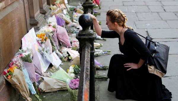 Женщина возлагает цветы жертвам нападения в Манчестере