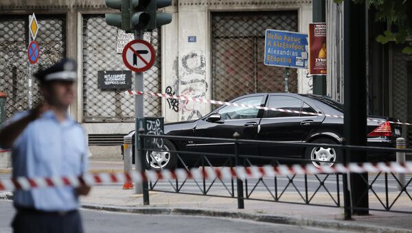 Полицейский возле автомобиля бывшего премьера Греции Лукаса Пападимоса после взрыва. Греция, 25 мая 2017