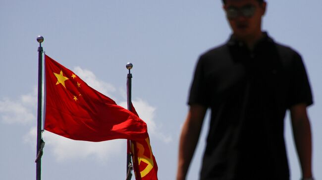 Мужчина рядом с национальным флагом Китая и флагом банка Китая в Пекине