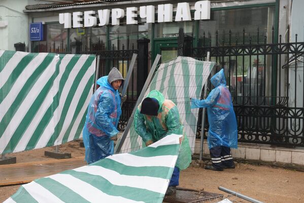 Строители поднимают сорванный ураганом заградительный забор на улице Остоженка в Москве