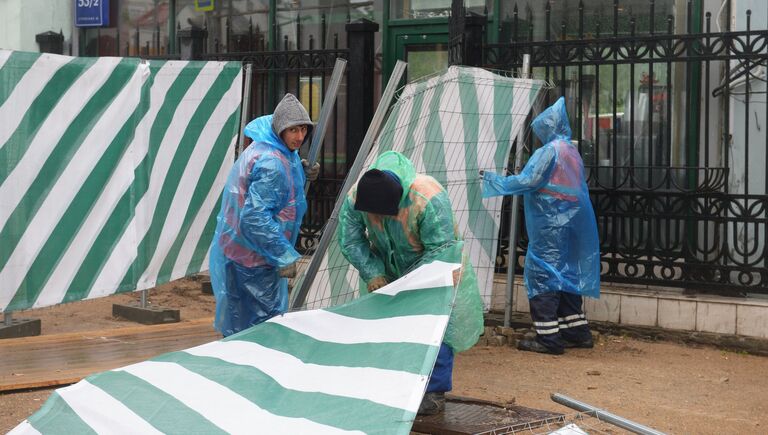 Строители поднимают сорванный ураганом заградительный забор на улице Остоженка в Москве