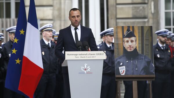 Парижанин Этьен Кардиль рядом с портретом своего партнера Ксавье Жюжеле, офицером полиции, убитым во время теракта на Елисейских полях