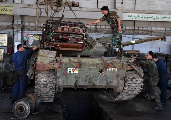 Рабочие устанавливают отремонтированный двигатель в одном из цехов завода по ремонту и восстановлению бронетанковой техники в Дамаске