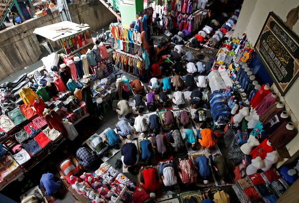 Мусульманские рабочие и владельцы магазинов во время пятничной молитвы на текстильном рынке в Индонезии