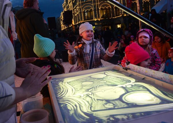 Дети на мастер-классе рисунка песком на стекле на фестивале Красная площадь в Москве
