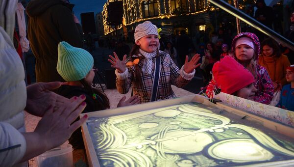 Дети на мастер-классе рисунка песком на стекле на фестивале Красная площадь в Москве
