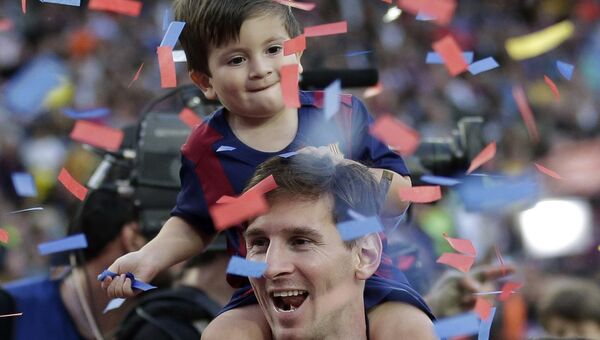 Нападающий футбольного клуба Барселона Лионель Месси с сыном радуются победе на стадионе в Барселоне
