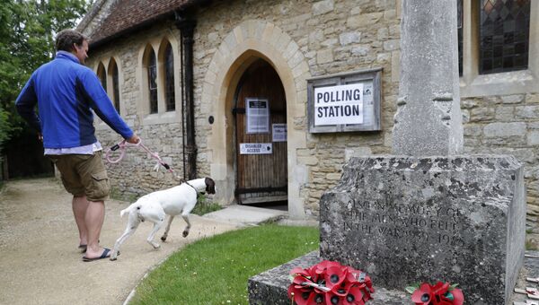 Мужчина с собакой возле участка для голосования на досрочных парламетских выборах в Великобритании. 8 июня 2017