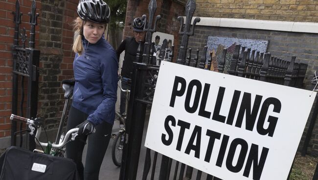Девушка выходит с избирательного участка в Лондоне